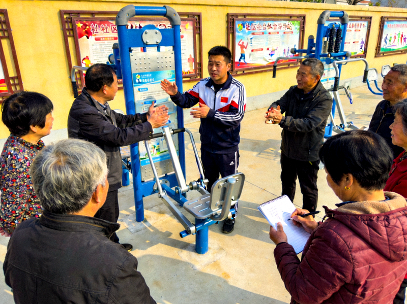 社区居民在健身指导站接受科学健身指导 - 社会体育指导员为居民讲解动作要领