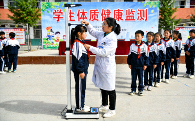 学生体质健康监测现场 - 医务人员为学生测量身高体重