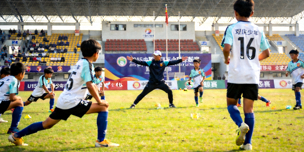 U15青少年足球赛事现场，小球员们在教练指导下进行赛前热身训练