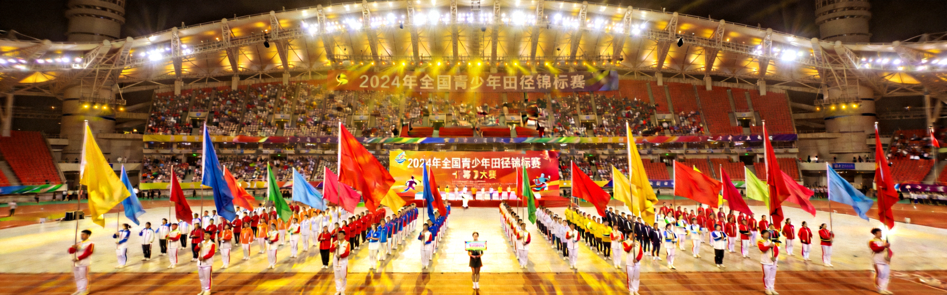 2024年全国青少年田径锦标赛开幕式全景 - 年轻运动员们在体育场中央集结，彩旗飘扬