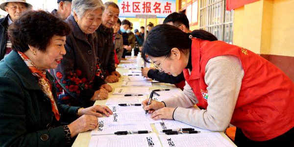 社区报名点居民踊跃咨询 - 志愿者协助填写报名表